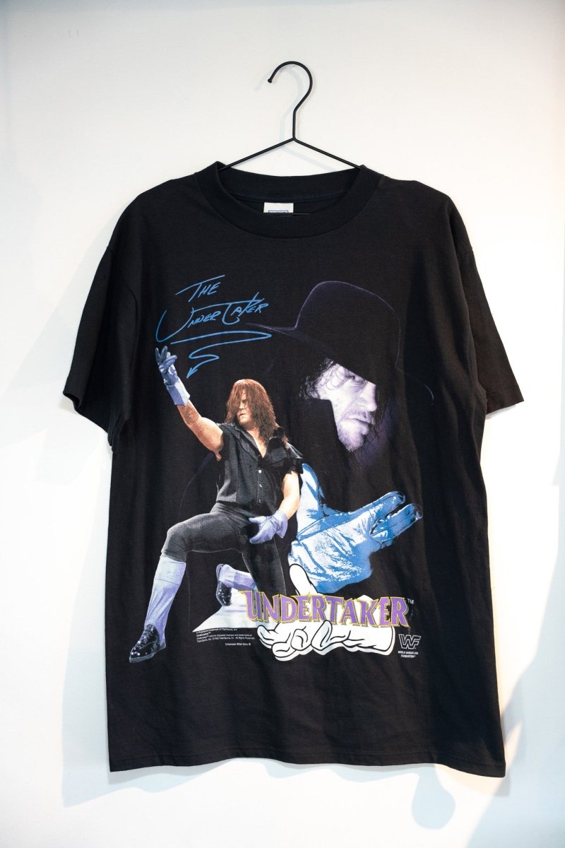 Black 1993 WWF Titan Sports Undertaker tee with full-body action shot and shadowed portrait blue script UNDERTAKER text WWF logo Wild Oats size Large