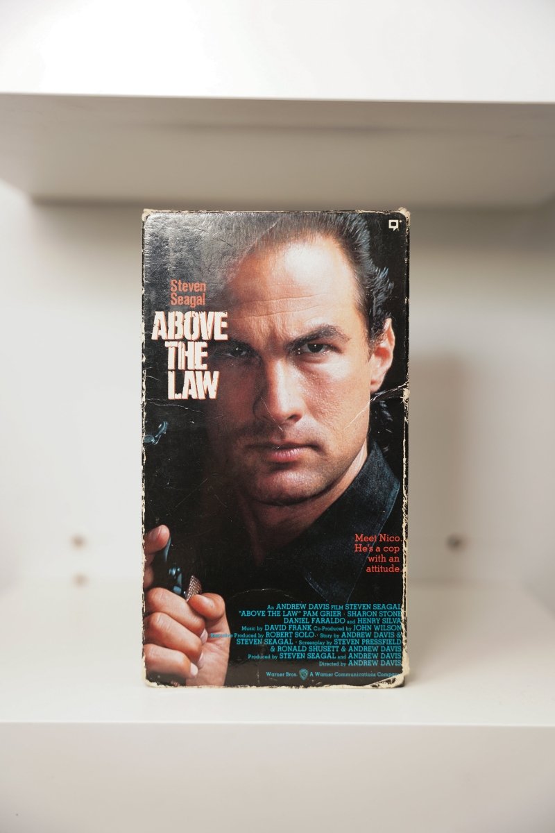 Above the Law VHS cover with Steven Seagal close-up holding gun in leather jacket, Meet Nico tagline, Warner Bros