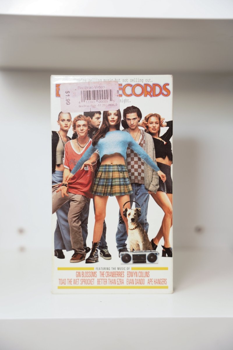 VHS Empire Records white cover ensemble cast Liv Tyler center blue top plaid skirt boombox dog EMPIRE RECORDS orange neon text soundtrack credits
