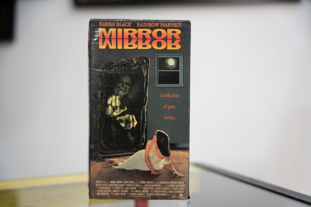 Mirror Mirror VHS dark sleeve with orange red reflected title ghoulish green face reaching through gothic mirror frame woman recoiling Academy Entertainment