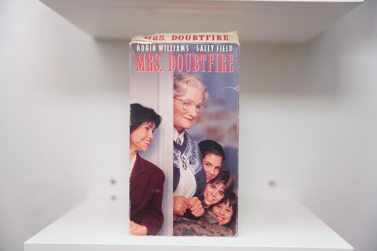 Mrs. Doubtfire VHS cover with Robin Williams in grey wig and glasses as Mrs. Doubtfire peering around door with children, Sally Field standing nearby