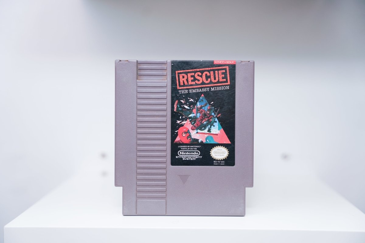 NES Rescue The Embassy Mission grey cartridge with red-suited operative crashing through window, RESCUE in red stamp text, Kemco-Seika logo
