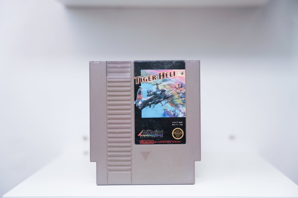 NES Tiger-Heli grey cartridge with futuristic attack helicopter in aerial combat amid explosions, Acclaim logo, Made in Japan