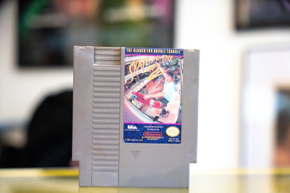 Nintendo NES Skate or Die 2 The Search for Double Trouble gray cartridge with fisheye skateboarding photo and yellow punk-style title lettering by Electronic Arts