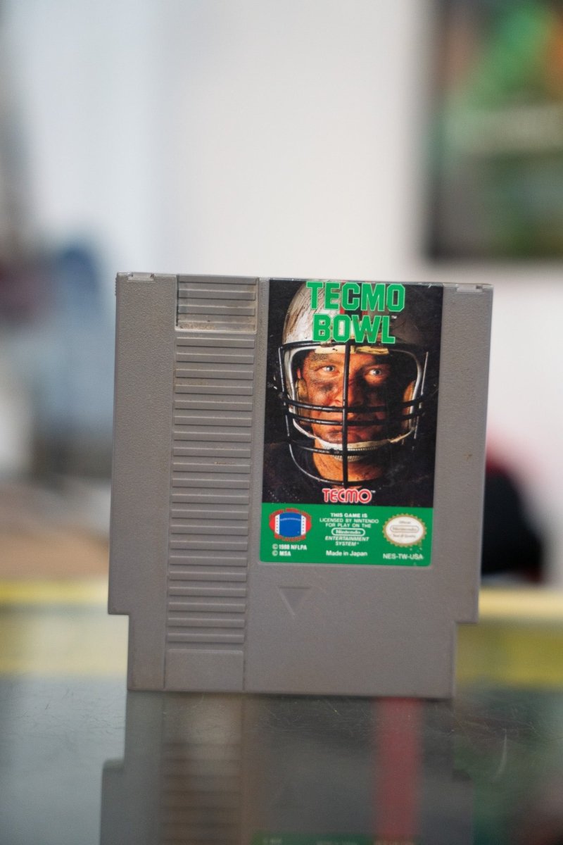 Nintendo NES Tecmo Bowl gray cartridge with football player facemask close-up and green metallic TECMO BOWL title