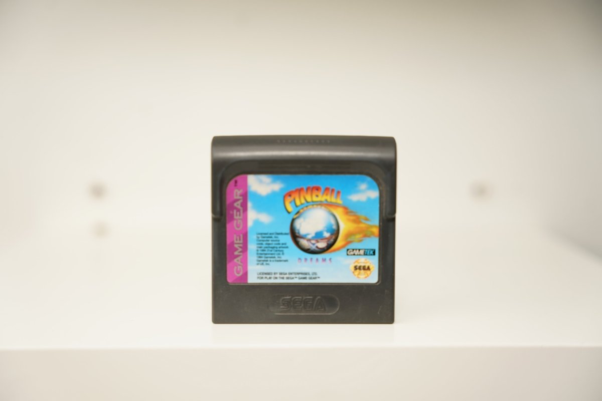 Sega Game Gear Pinball Dreams cartridge with flaming chrome pinball against blue sky, GameTek logo, pink Game Gear spine text