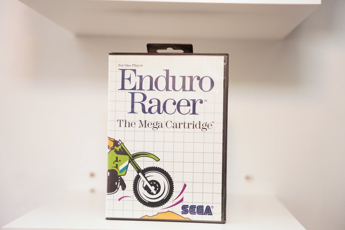 Sega Master System Enduro Racer clamshell case with cartoon motocross rider on green dirt bike catching air, The Mega Cartridge subtitle