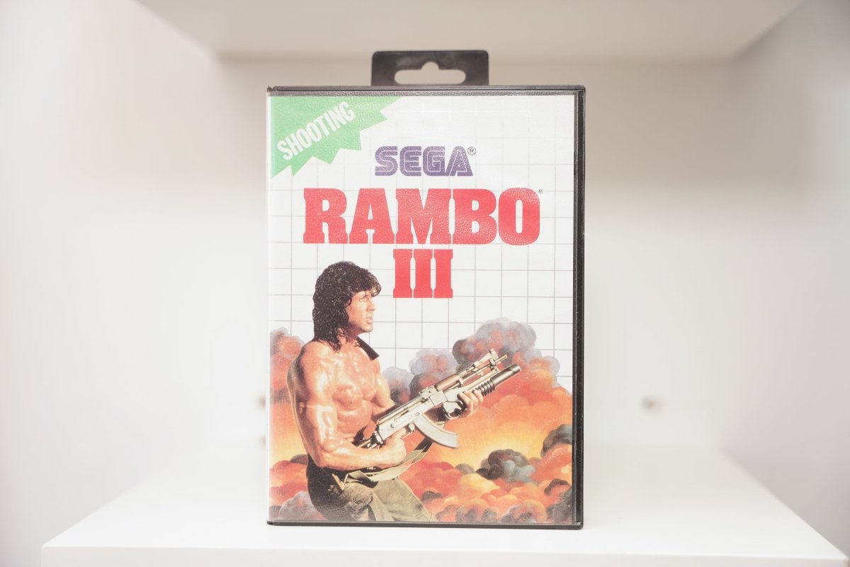 Sega Master System Rambo III clamshell case with Rambo holding weapon amid explosions, green Shooting category banner, Sega logo