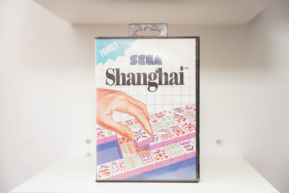 Sega Master System Shanghai clamshell case with hand selecting Mahjong tile from layered arrangement, blue Family category banner, Sega logo