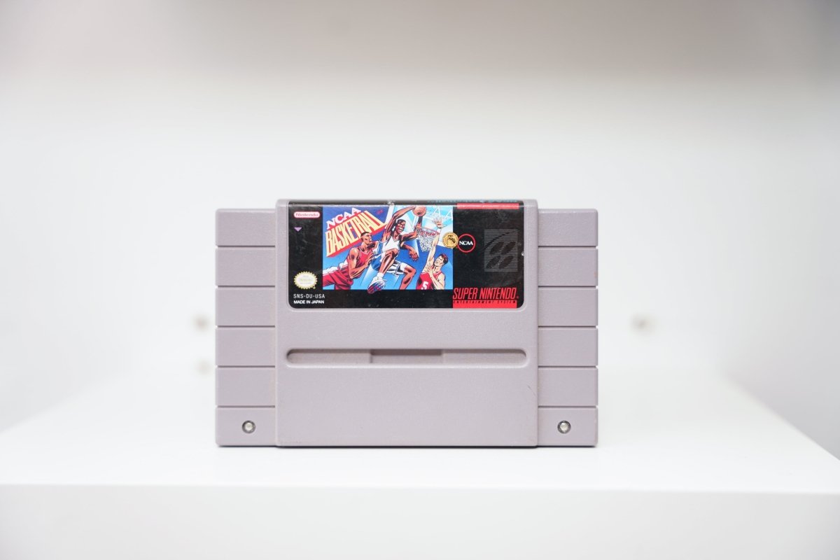 SNES NCAA Basketball grey cartridge with cartoon basketball players dunking in red and blue uniforms, NCAA logo, Nintendo publisher