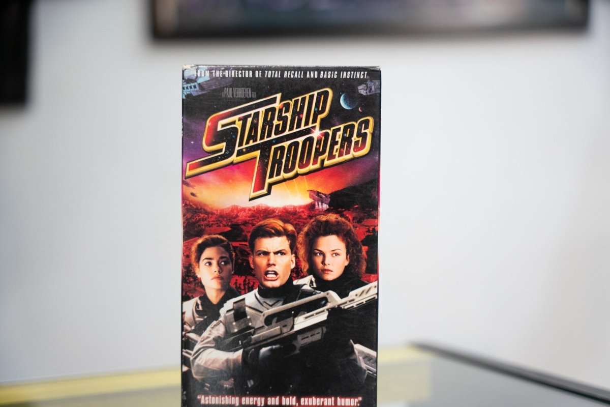 Starship Troopers VHS with Casper Van Dien Denise Richards Dina Meyer in armor fiery alien planet gold red metallic title and Total Recall director credit