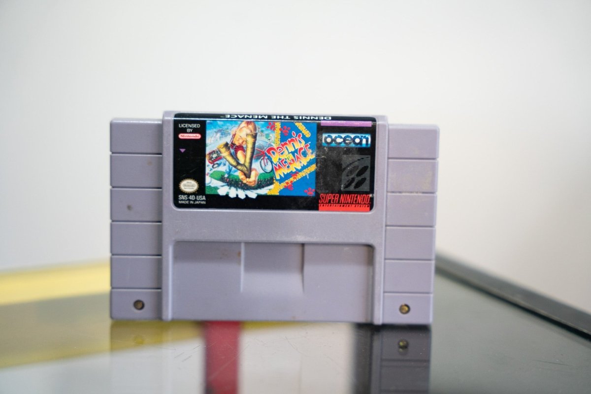 Super Nintendo Dennis the Menace gray SNES cartridge with colorful label Dennis skateboarding Ocean logo Licensed by Nintendo