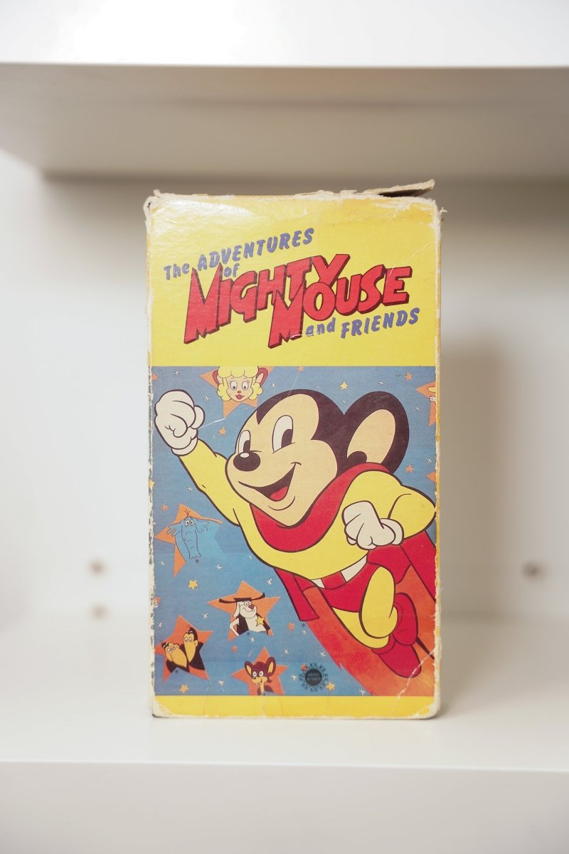 The Adventures of Mighty Mouse and Friends VHS cover with Mighty Mouse flying in red cape and yellow suit surrounded by cartoon friends on blue starry background