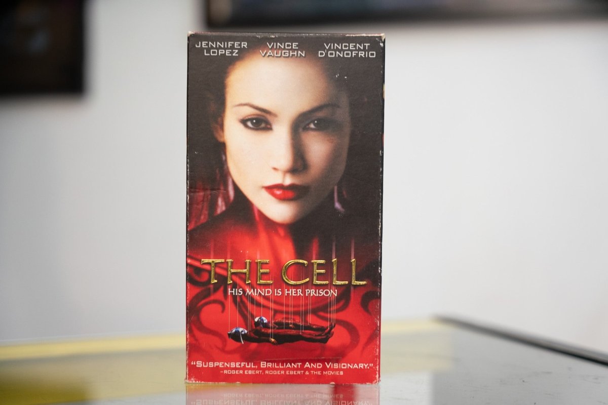 The Cell VHS with red-toned Jennifer Lopez close-up face gold THE CELL ornate title His Mind Is Her Prison tagline and Roger Ebert quote