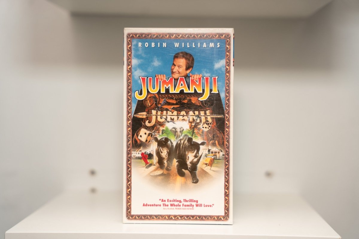 VHS Jumanji Robin Williams peeking over board game rhinoceros stampede blue sky tropical foliage JUMANJI gold green text TriStar