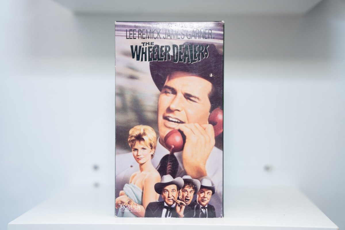 VHS The Wheeler Dealers painted cover James Garner cowboy hat red telephone Lee Remick elegant dress THE WHEELER DEALERS white text MGM/UA