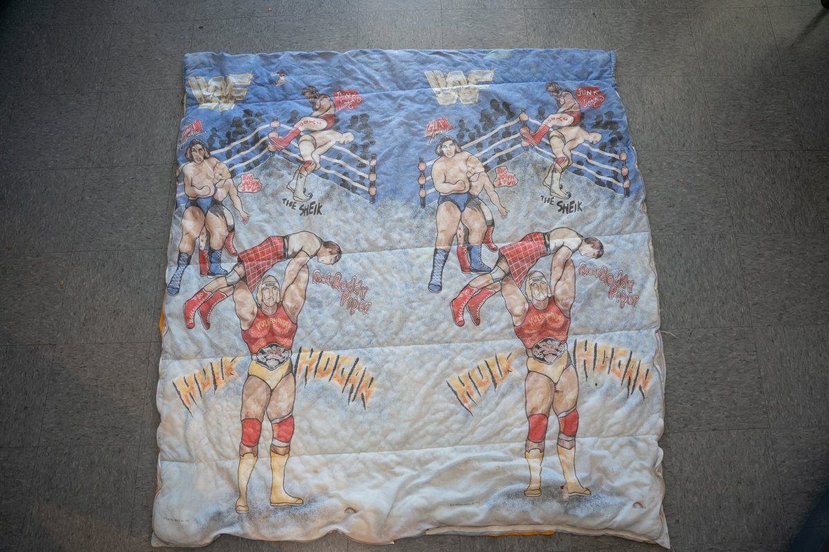 WWF 1980s wrestling comforter featuring Hulk Hogan, Roddy Piper, Junk Yard Dog and The Sheik, red and yellow quilted fabric with broken zipper