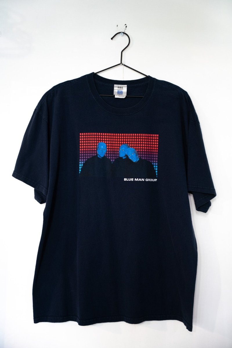 Navy blue vintage Blue Man Group tee with rectangular photo of three blue-painted performers pixel grid background white text size XL