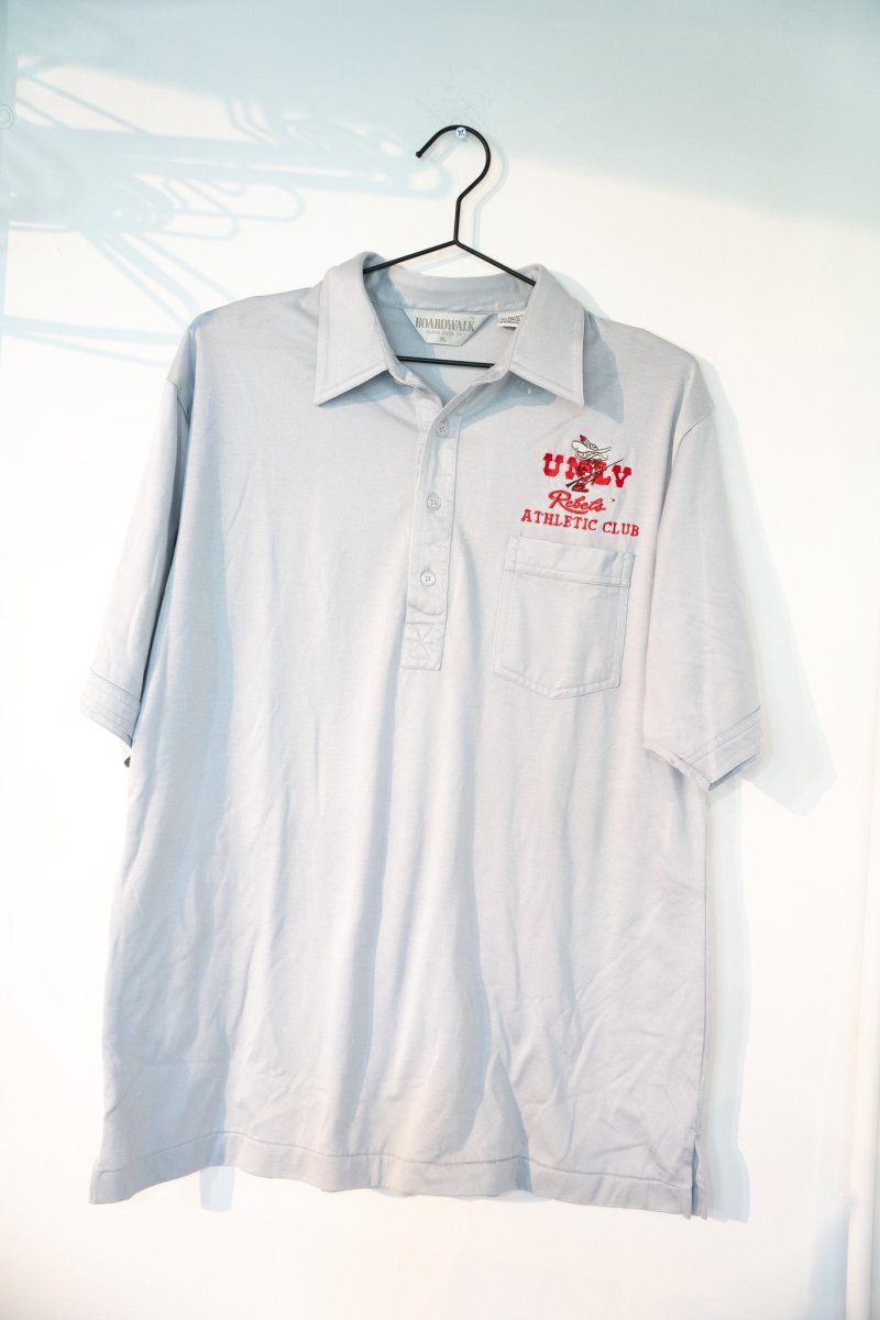 Light gray vintage Boardwalk UNLV Rebels Athletic Club polo shirt with red UNLV embroidery Hey Reb mascot chest pocket three button placket size XL