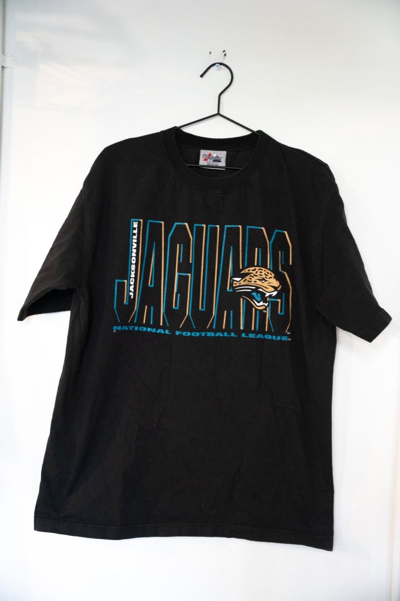 Black vintage Majestic Jacksonville Jaguars shirt with teal JACKSONVILLE text, outlined JAGUARS lettering, and snarling jaguar head logo