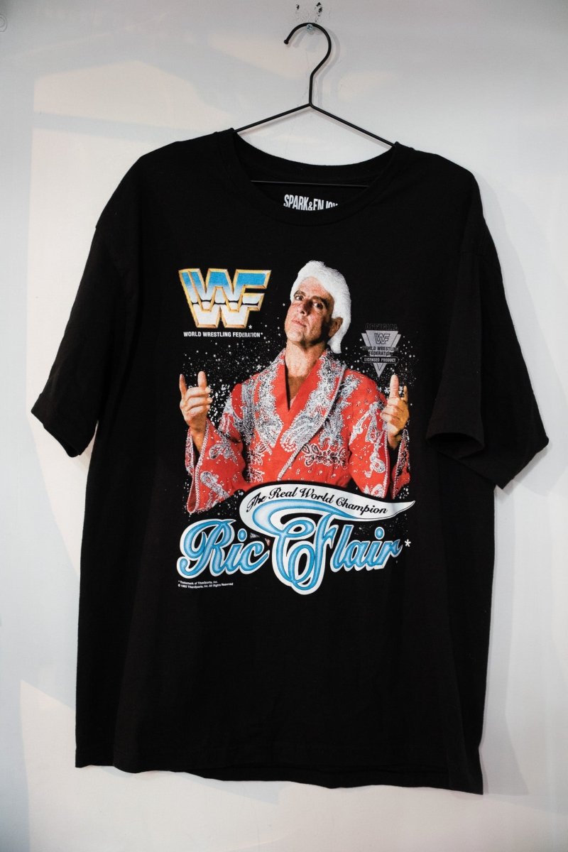 Black WWF Ric Flair The Real World Champion tee with Flair in red sequined robe and blue Ric Flair script below