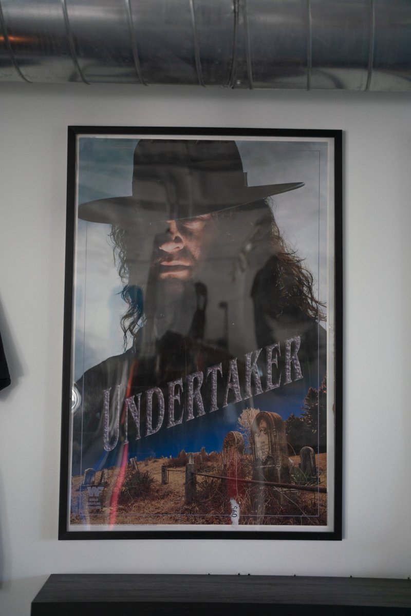 Framed 1992 WWF Titan Sports The Undertaker poster with Taker in black hat cemetery scene headstones dark sky stone UNDERTAKER text WWF logo