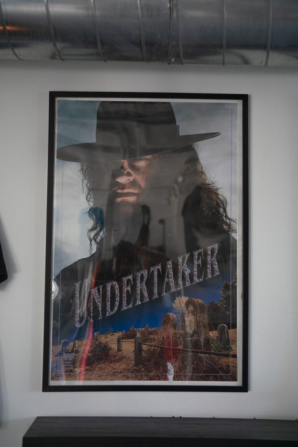 Framed 1992 WWF Titan Sports The Undertaker poster with Taker in black hat cemetery scene headstones dark sky stone UNDERTAKER text WWF logo
