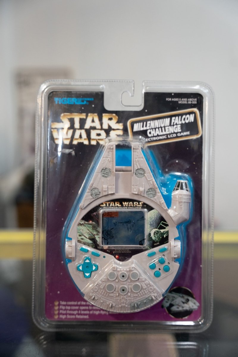Sealed 1997 Tiger Electronics Star Wars Millennium Falcon Challenge LCD handheld game shaped like the Falcon on purple starfield card