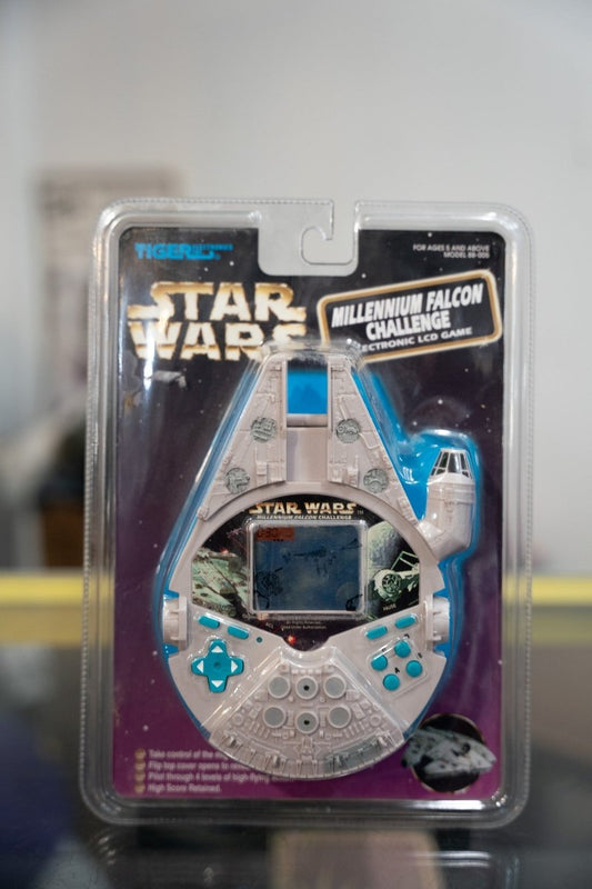 Sealed 1997 Tiger Electronics Star Wars Millennium Falcon Challenge LCD handheld game shaped like the Falcon on purple starfield card