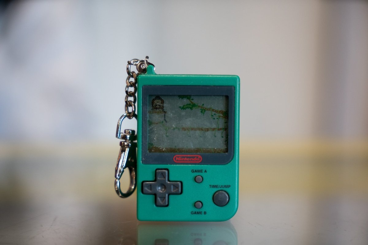 Green 1998 Nintendo Mini Game Boy keychain with Donkey Kong Jr LCD game screen showing vine climbing gameplay with red Nintendo logo