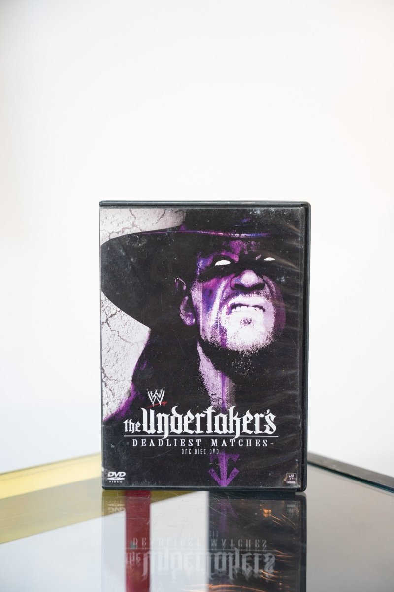 WWE The Undertaker's Deadliest Matches DVD dark purple cover Undertaker close-up face under hat brim purple lighting gothic script metallic text