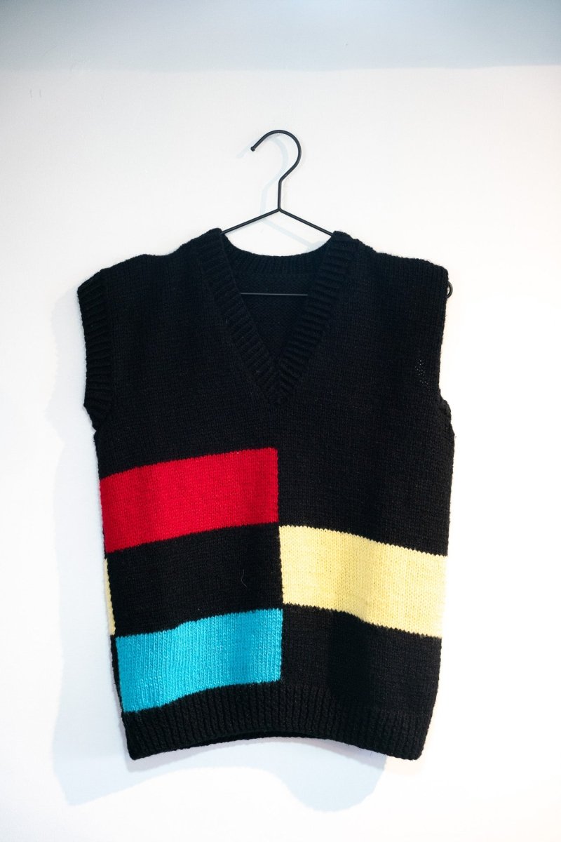 Black 90s V-neck sweater vest with asymmetric red yellow teal color blocks Mondrian-style geometric knit ribbed trim size Small