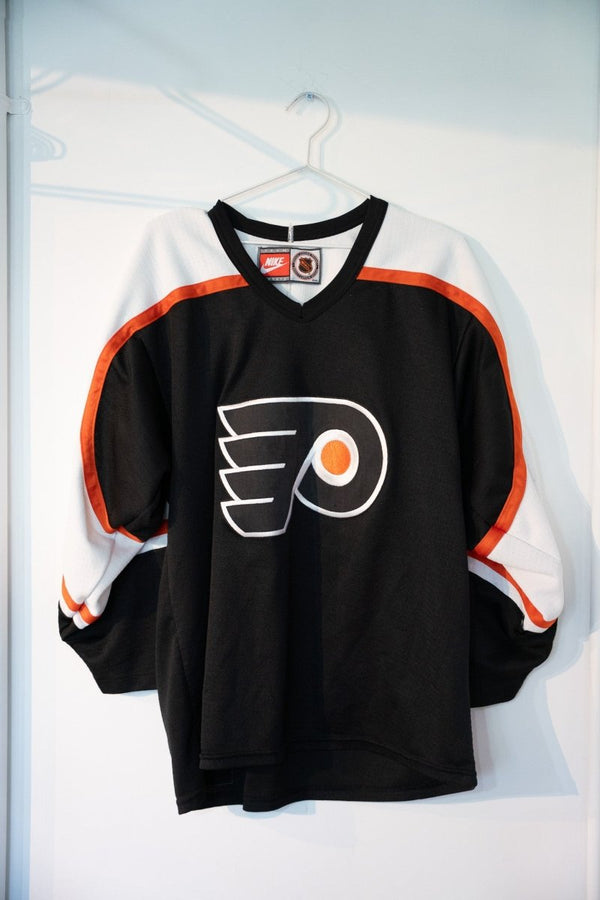 Black 90s Nike Philadelphia Flyers hockey jersey with large white orange winged P logo white shoulder panels orange striped cuffs mesh size Medium