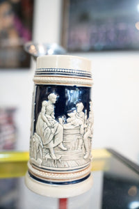 Collectible antique German lidded beer stein with ceramic body and metal hinged lid, featuring traditional decorative glazing and handle