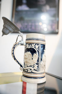 Collectible German beer stein with lid, ceramic body featuring decorative glazed finish and metal hinged cover, antique style