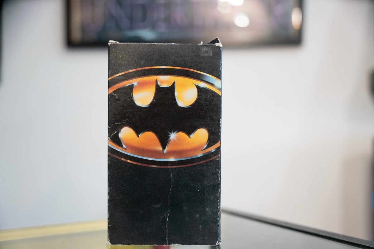 Batman VHS black sleeve with iconic gold Batman bat symbol in oval gleaming metallic on pure black background Warner Bros 1989