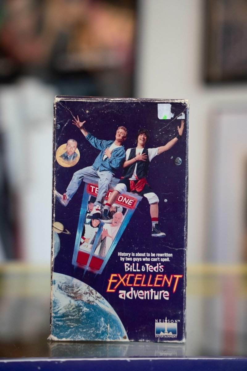 Bill and Ted's Excellent Adventure VHS tape with Keanu Reeves and Alex Winter on time-traveling phone booth above Earth