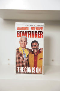 Bowfinger VHS Special Edition cover with Steve Martin in plaid jacket and Eddie Murphy in glasses smiling, The Con Is On tagline