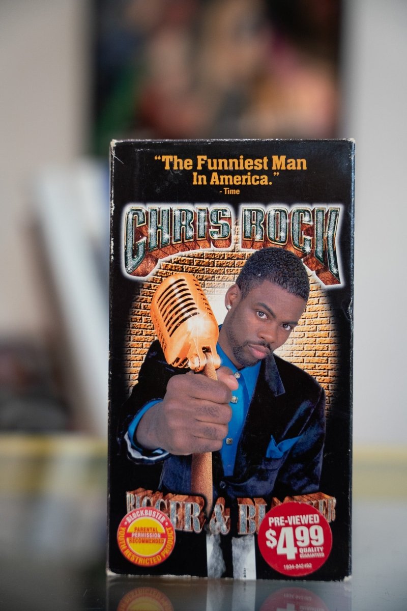 Chris Rock Bigger and Blacker VHS with Rock in suit gripping gold microphone against brick wall with ornate gold CHRIS ROCK lettering