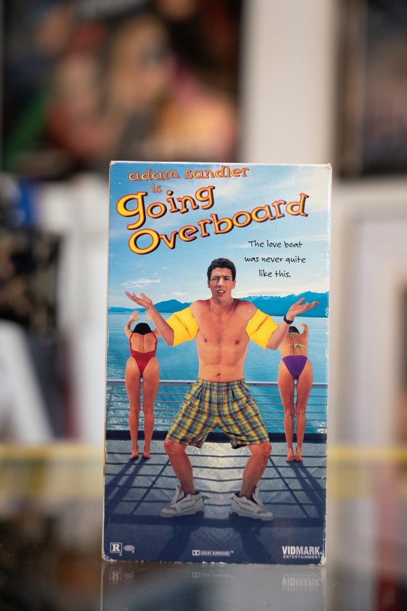 Going Overboard VHS tape with young Adam Sandler shirtless in plaid shorts on cruise ship deck with orange Going Overboard title
