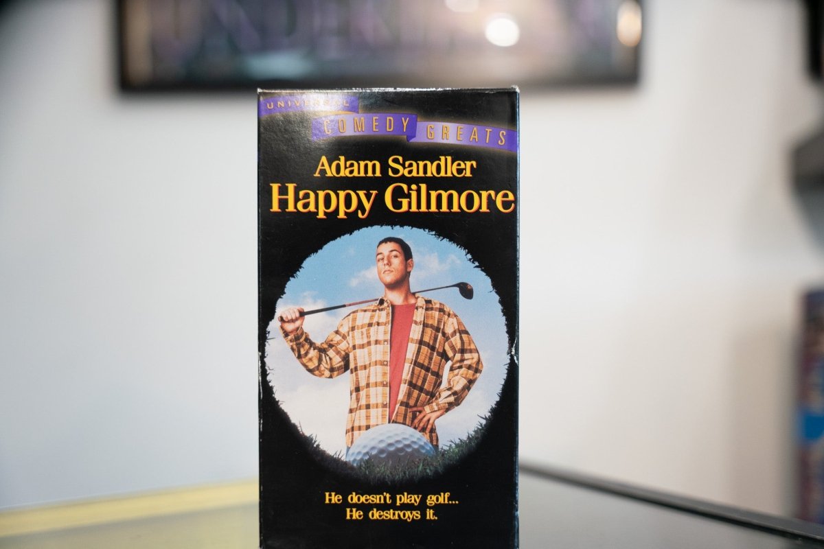 Happy Gilmore VHS black sleeve Universal Comedy Greats banner Adam Sandler plaid flannel golf club golf ball gold title He Destroys It tagline