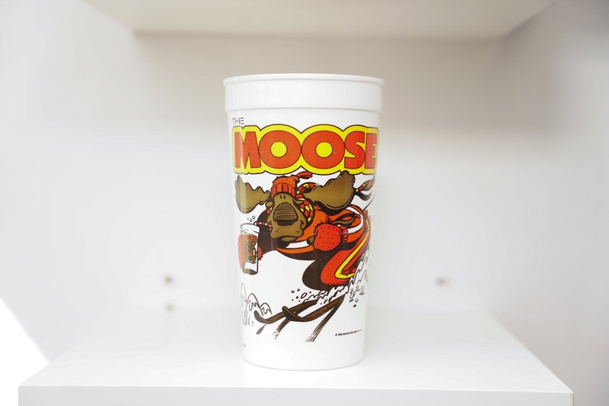 Hardee's The Moose white plastic cup with cartoon moose skiing in red winter gear, yellow and red block letter title