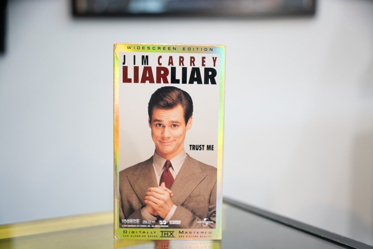 Liar Liar VHS widescreen holographic gold border Jim Carrey beige suit red tie clasped hands black red LIAR LIAR title Trust Me THX Universal