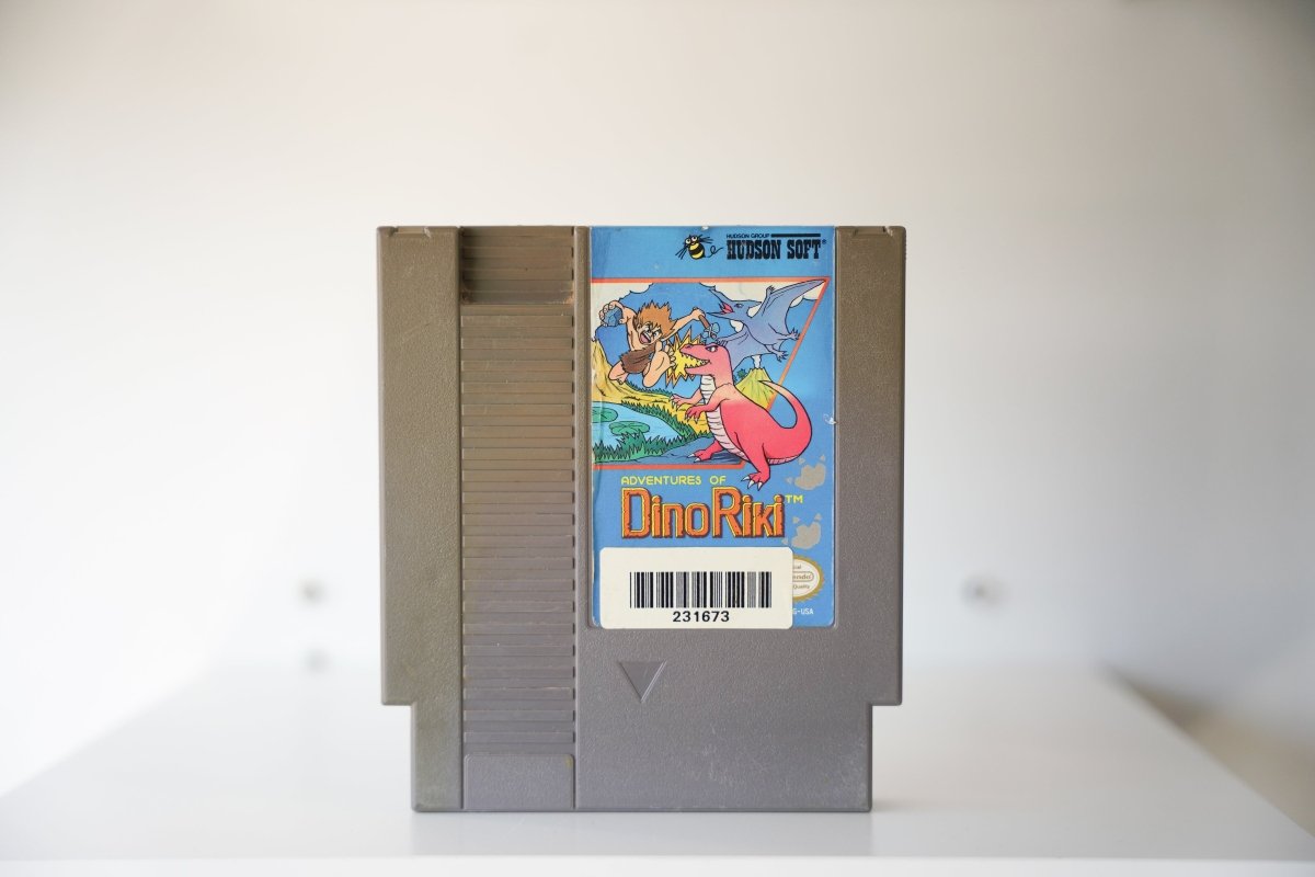 NES Adventures of Dino Riki gray cartridge caveman boy pink dinosaur pterodactyl HUDSON SOFT logo Adventures of Dino Riki text Nintendo
