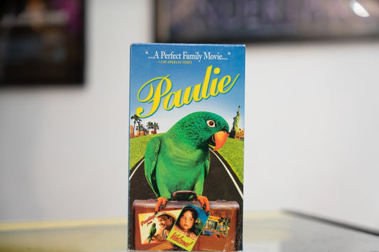 Blue Paulie VHS with green parrot carrying suitcase on road yellow Paulie cursive title and Los Angeles Times Perfect Family Movie quote