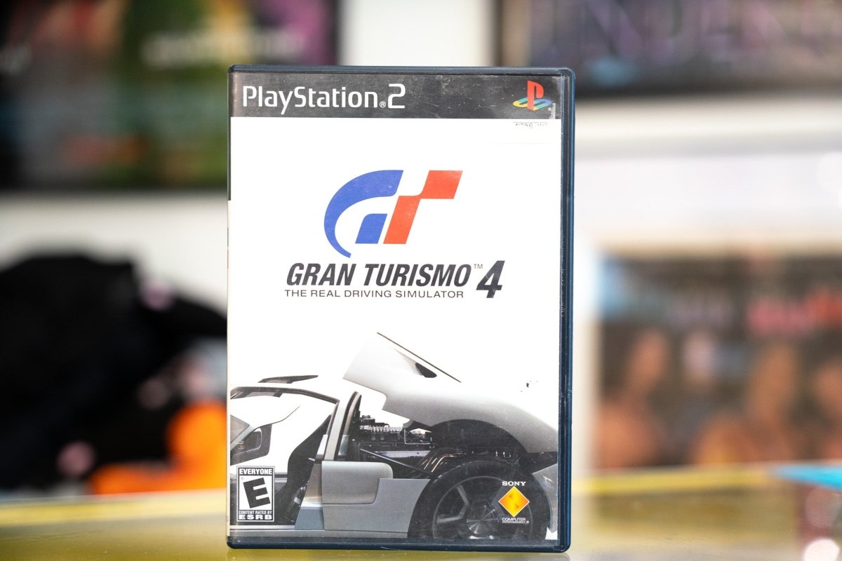PlayStation 2 Gran Turismo 4 case with white minimalist cover blue and red GT logo silver GRAN TURISMO 4 title and silver race car rear view