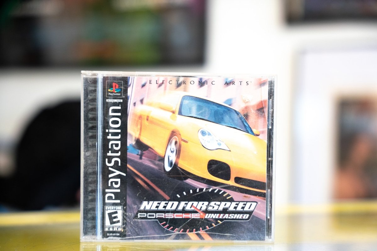 PlayStation Need for Speed Porsche Unleashed jewel case with yellow Porsche 911 racing at speed speedometer overlay and white silver title
