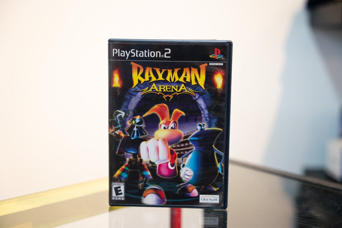 PlayStation 2 Rayman Arena black PS2 case Rayman fighting stance flaming torches arena RAYMAN gold text Arena silver Ubi Soft Everyone