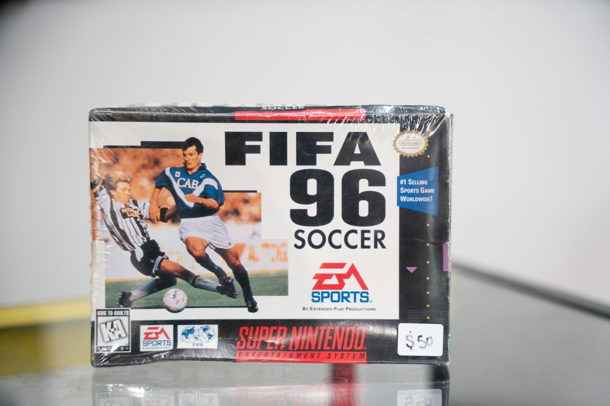 SNES FIFA 96 Soccer box with soccer player in blue jersey dribbling, EA Sports logo, #1 Selling Sports Game seal, appears sealed with $50 sticker
