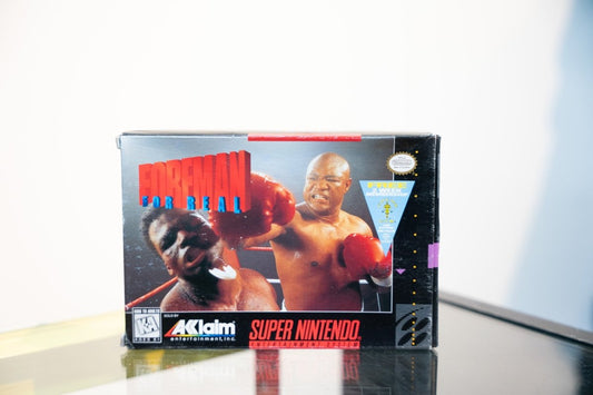 SNES Foreman For Real box with George Foreman delivering right hook in red boxing gloves, Acclaim logo, promotional sticker